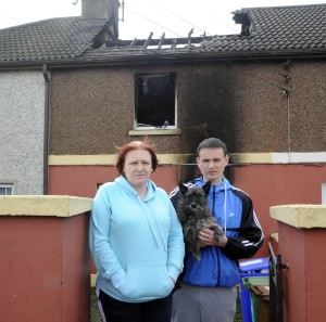 Marie and Jordan Phillips with Lexy pictured outside the remains of their home. Pic: Jim Campbell